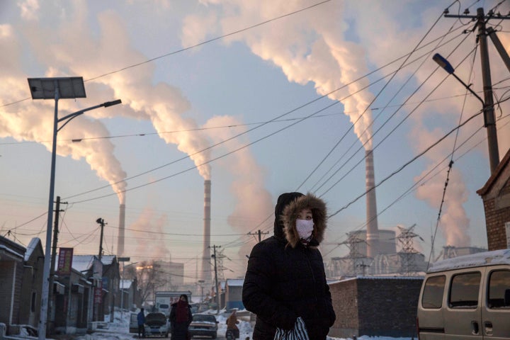 A woman wears as mask while walking in a neighborhood next to a coal-fired power plant on Nov. 26, 2015, in Shanxi, China.