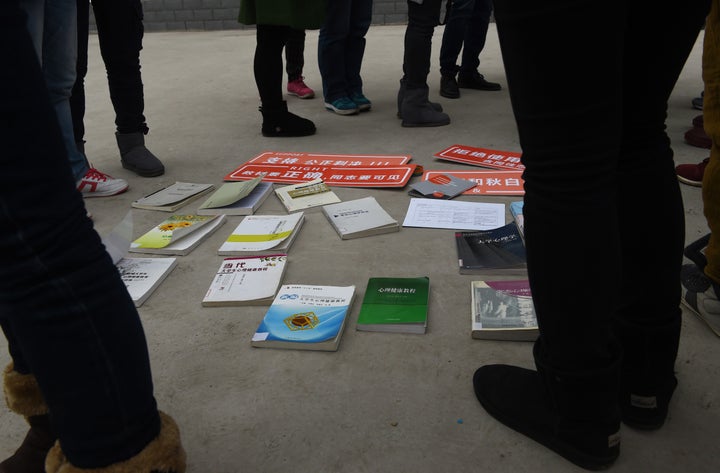 LGBT activists and journalists stand around textbooks they say present being gay as a disease or psychological disorder.