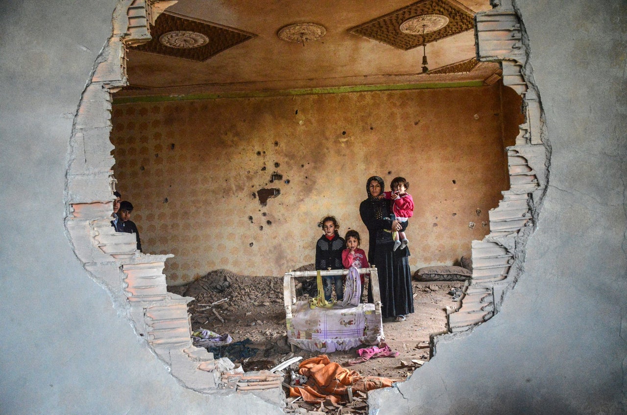 A woman and her children stand in the ruins of a house in the Kurdish town of Silopi on Jan. 19. Turkish forces are fighting to rout a youth militia that is entrenched in several areas of southeast Turkey.