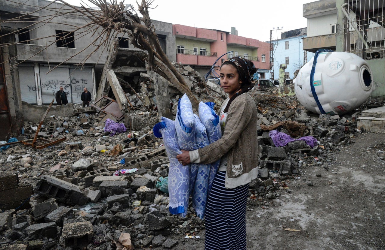 A woman retrieves bedding from the ruins of a house in Silopi. The town was under round-the-clock curfew for 36 days until it was partially lifted last week.