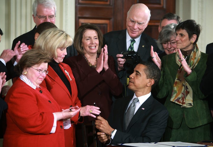 U.S. President Barack Obama (C) hands Lilly Ledbetter a pen after signing the Lilly Ledbetter Fair Pay Act during an event in the East Room of the White House January 29, 2009, in Washington, D.C.