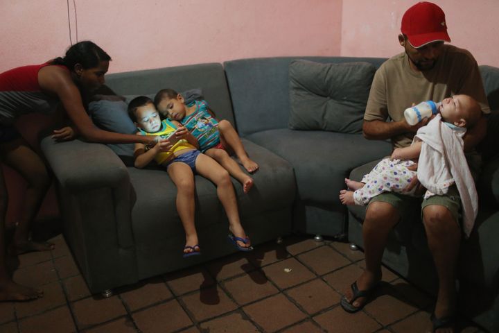 David Henrique Ferreira (R), 5 months, who was born with microcephaly, is fed by his grandfather Severino Vicente as other family members gather on January 29, 2016 in Recife, Pernambuco state, Brazil.