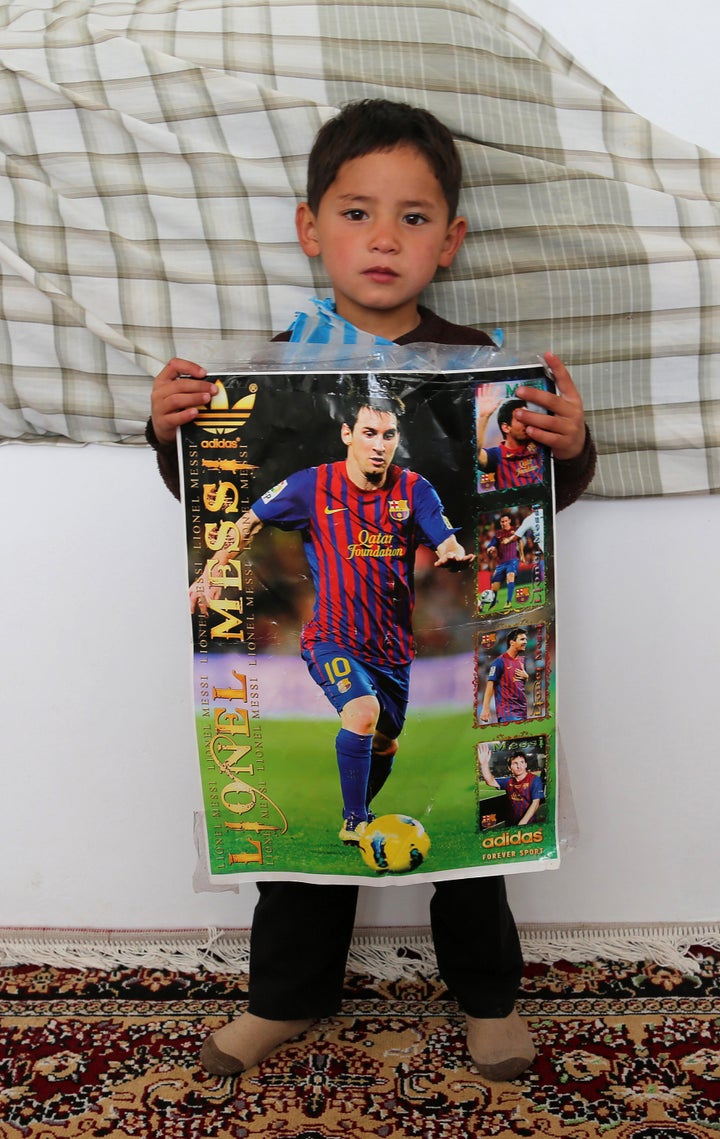 Murtaza wears a plastic bag jersey as he holds a photo of his hero.