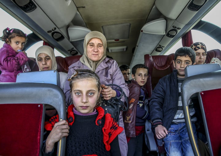 Groups of refugees were transported across the Syrian-Turkish border in buses.