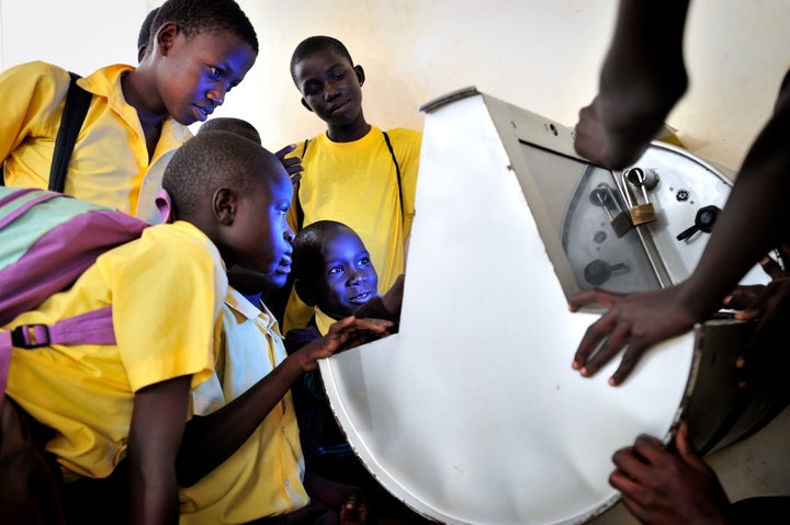 Young Ugandans gather around to use UNICEF's unique innovation the solar-powered Digital Drum, at Bosco Youth Centre in Gulu, Uganda.