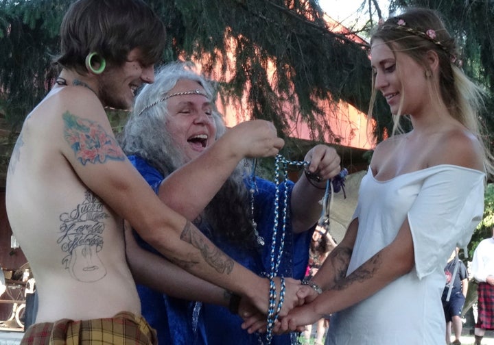 Selena Fox ties the handfasting cords during a couple's wedding ceremony at Pagan Spirit Gathering.