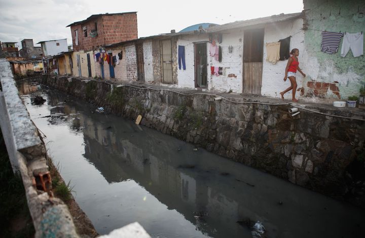 A young woman walks in a community along a polluted canal on February 3, 2016 in Recife, Pernambuco state, Brazil. Residents said several members of the community were currently sick with mosquito-related illnesses including the Zika virus.