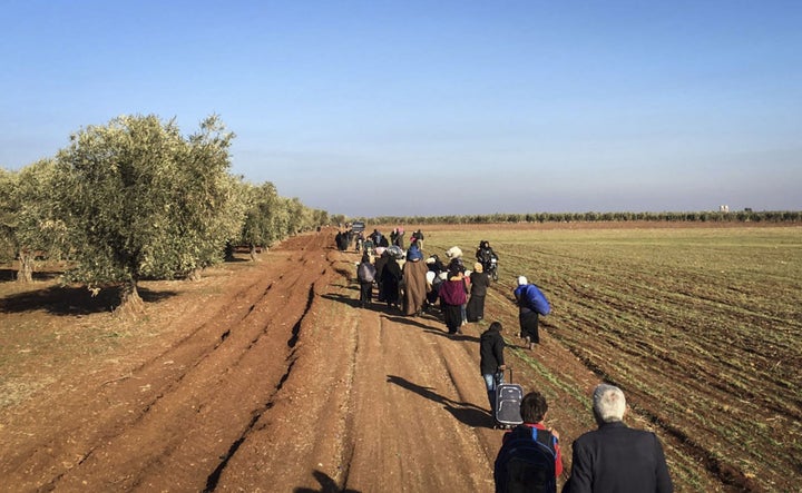 Syrians walk on a field as they migrate to Azaz region of Aleppo after Russian jets carried out airstrikes on opposition controlled regions. 