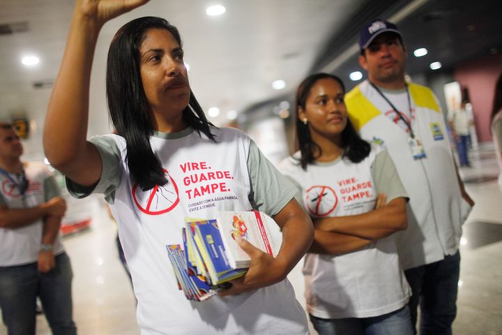 Health workers pass out information on mosquito protection to people arriving in the baggage claim area at Guararapes Gilberto Freyre International Airport on February 4, 2016 in Recife, Pernambuco state, Brazil. Officials say as many as 100,000 people may have already been exposed to the Zika virus in Recife, although most never develop symptoms. 