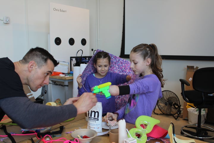 Boatright helping Sydney design her “dual water gun wearable” activated by elbow movement that she created to help her beat her siblings in water gun fights.