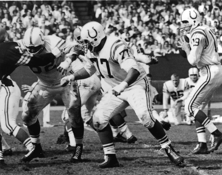 American professional football player Jim Parker (center), offensive tackle for the Baltimore Colts, blocks an opposing player while quarterback Johnny Unitas prepares to throw the ball during a game, late 1950s or 1960s.