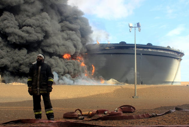 A Libyan firefighter&nbsp;stands in front of&nbsp;smoke billowing&nbsp;from an oil storage tank that...