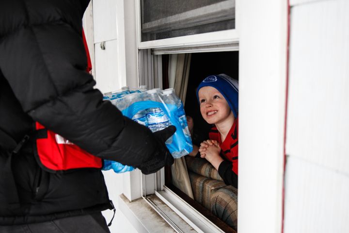Jake McSigue, 6, receives a package of bottled water through the window of his grandma's home on Jan. 21, 2016 in Flint, Michigan. McSigue was home sick from school and staying with his grandma, whose front door does not open. Thousands of people have volunteered to distribute water in Flint.