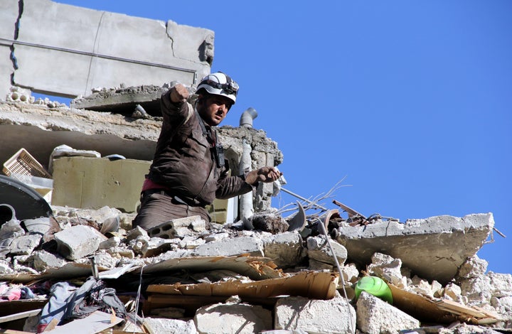 A man searches for survivors under the debris following Russian airstrikes in Aleppo. 