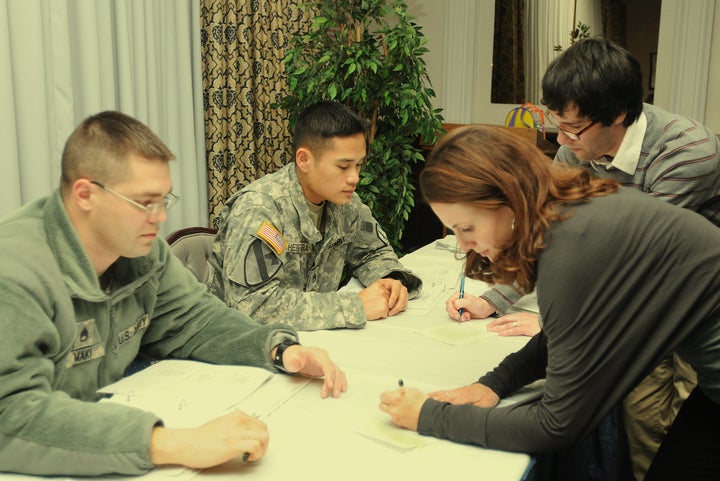 Facilitators from the University of New Hampshire sign the pledges of Staff Sgt. Oliver Herrera and Staff Sgt. Joseph Maki during a U.S. Army workshop on bystander intervention. 