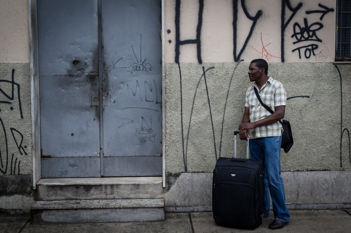 A Haitian man stands with his suitcase and waits at the entrance of a shelter for immigrants and refugees in Sao Paulo on Jan. 15, 2012.