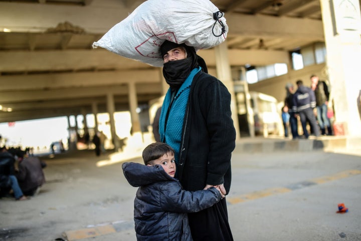 A woman and child wait at the Bab al-Salama border crossing between Syria and Turkey, which lies north of Aleppo, on Friday.