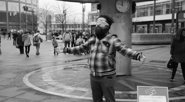 Firas Alshater, a Syrian asylee, is the star of a new video series that examines German society from an asylum seeker's point of view. In his first video, he stands blindfolded in the middle of Berlin's Alexanderplatz asking people to hug him.