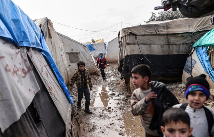 Refugee children walk between tents at a camp near the Turkish border crossing gate as Syrians fleeing the northern embattled