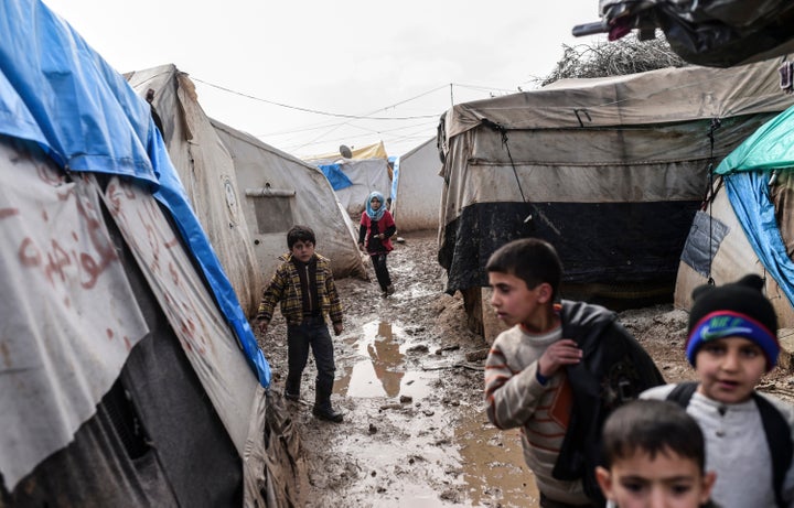 Refugee children walk between tents at a camp near the Turkish border crossing gate as Syrians fleeing the northern embattled city of Aleppo wait on February 6, 2016 in Bab-Al Salam, near the city of Azaz, northern Syria.