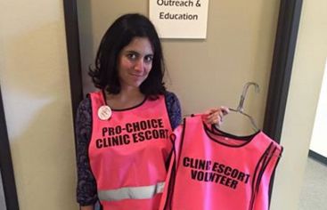 An escort for a Sacramento women's health clinic uses the coat hangers left by anti-abortion protestors to hang their clinic escort vests. 