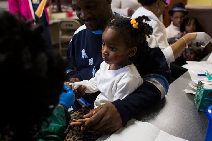 Azariah Hawthorne, 2, is held by her grandfather Nile Hawthorne Sr., 46, as she gets her blood lead levels tested at Carriage Town Ministries in Flint, Michigan, on Feb. 4, 2016. Hawthorne has been on bottled water most of her life due to the city's ongoing water crisis.