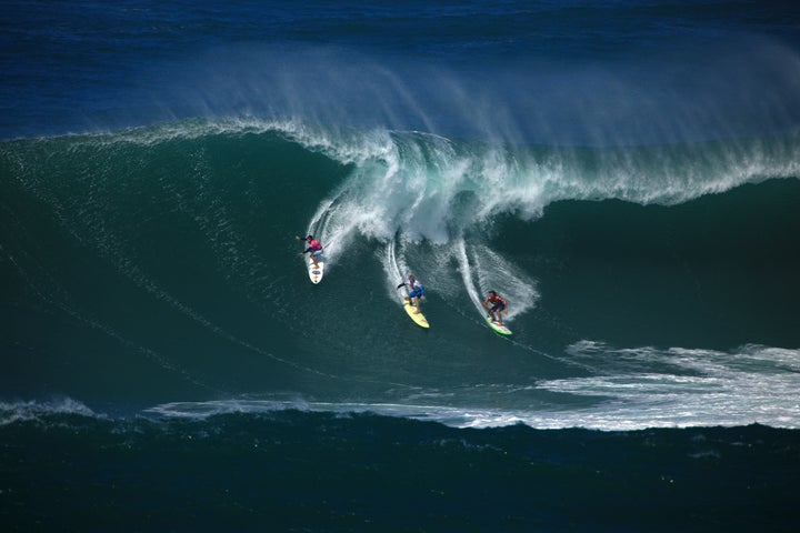 Surfers ride a wave during the 2009 Eddie Aikau Big Wave Invitational at Waimea Bay.