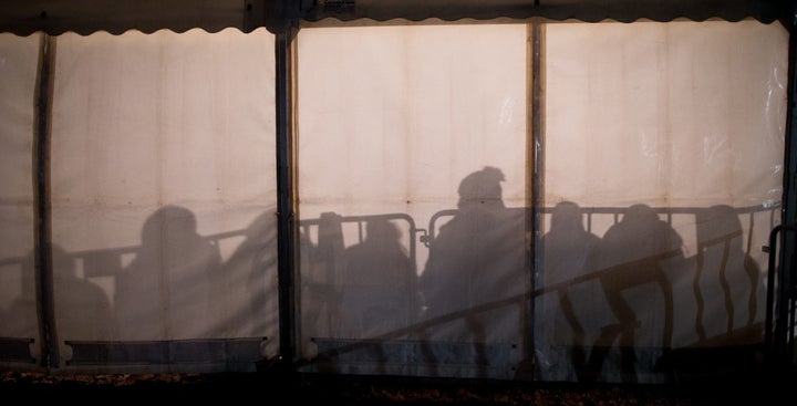 The shadows of asylum-seekers waiting for their registration are cast against the wall of a tent in front of the State Office