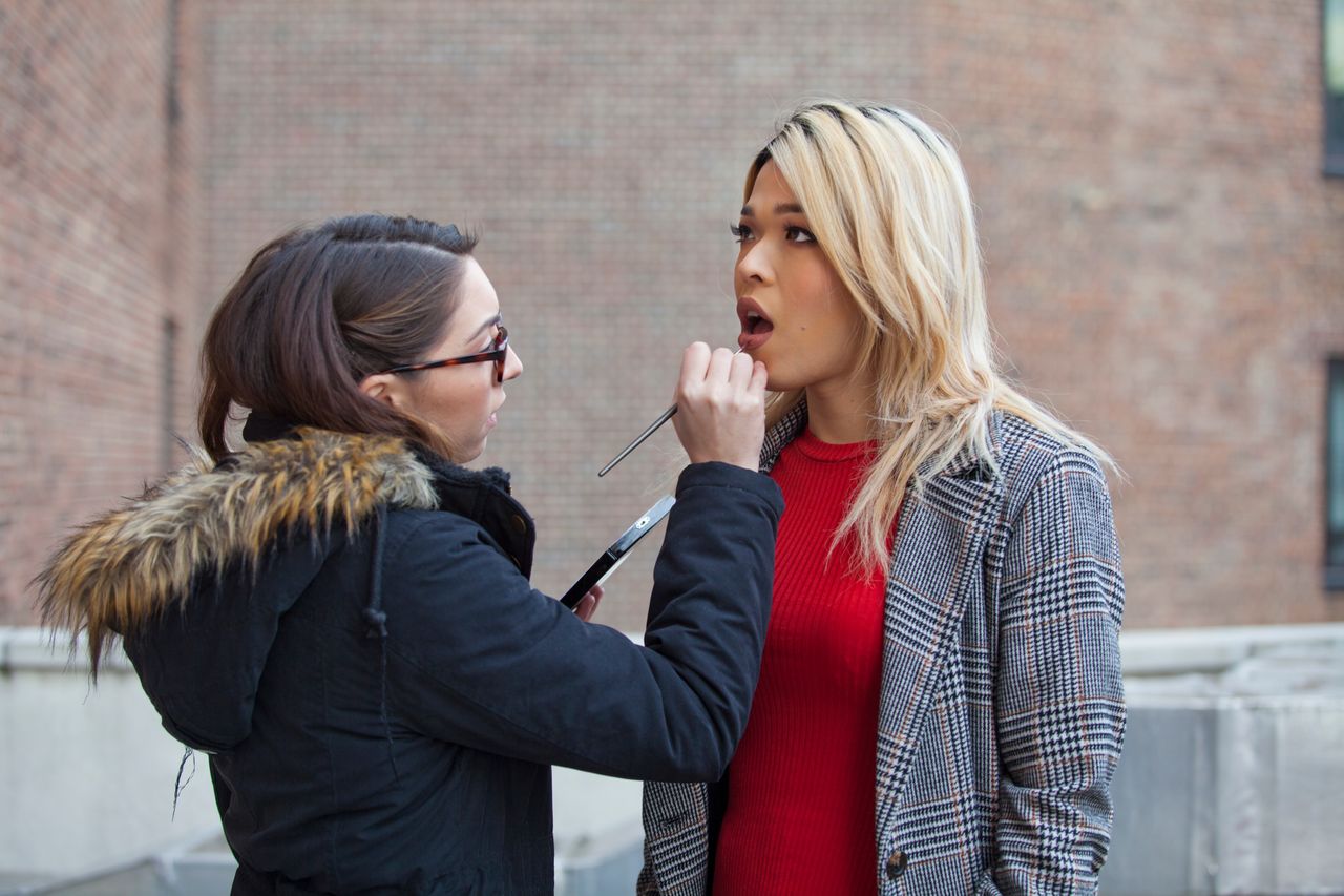 The makeup artist applies lipstick for Vikki Le prior to a fashion shoot.