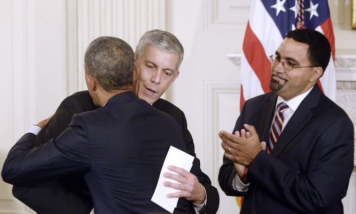 President Barack Obama hugs outgoing Secretary of Education Arne Duncan as his nominee to replace Duncan, John B. King Jr., looks on in October 2015.