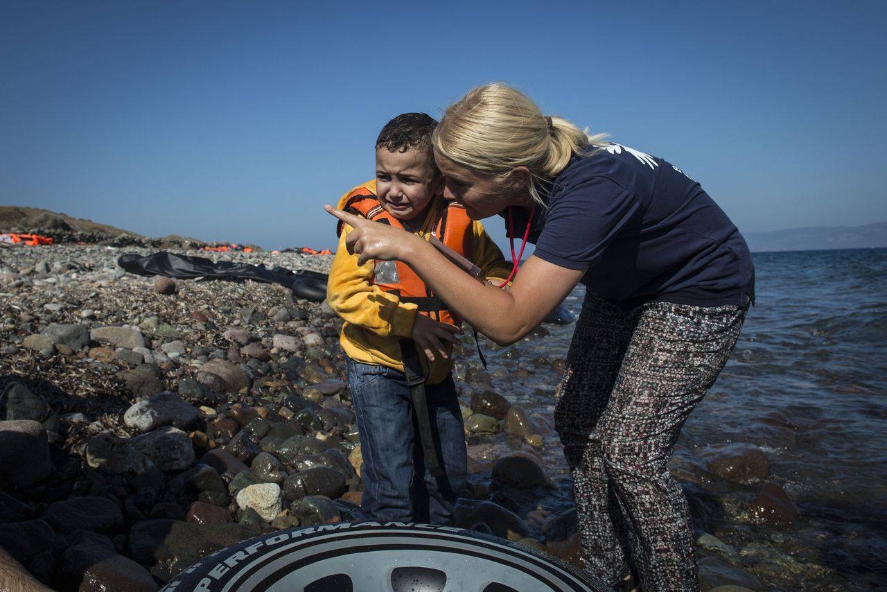 A European volunteer talks to a crying refugee toddler after refugee boat arrived in Lesbos Island, Greece on September 17, 2015. European volunteers who came to Greece's Lesbos Island provide food, drinks and clothing for refugees. 