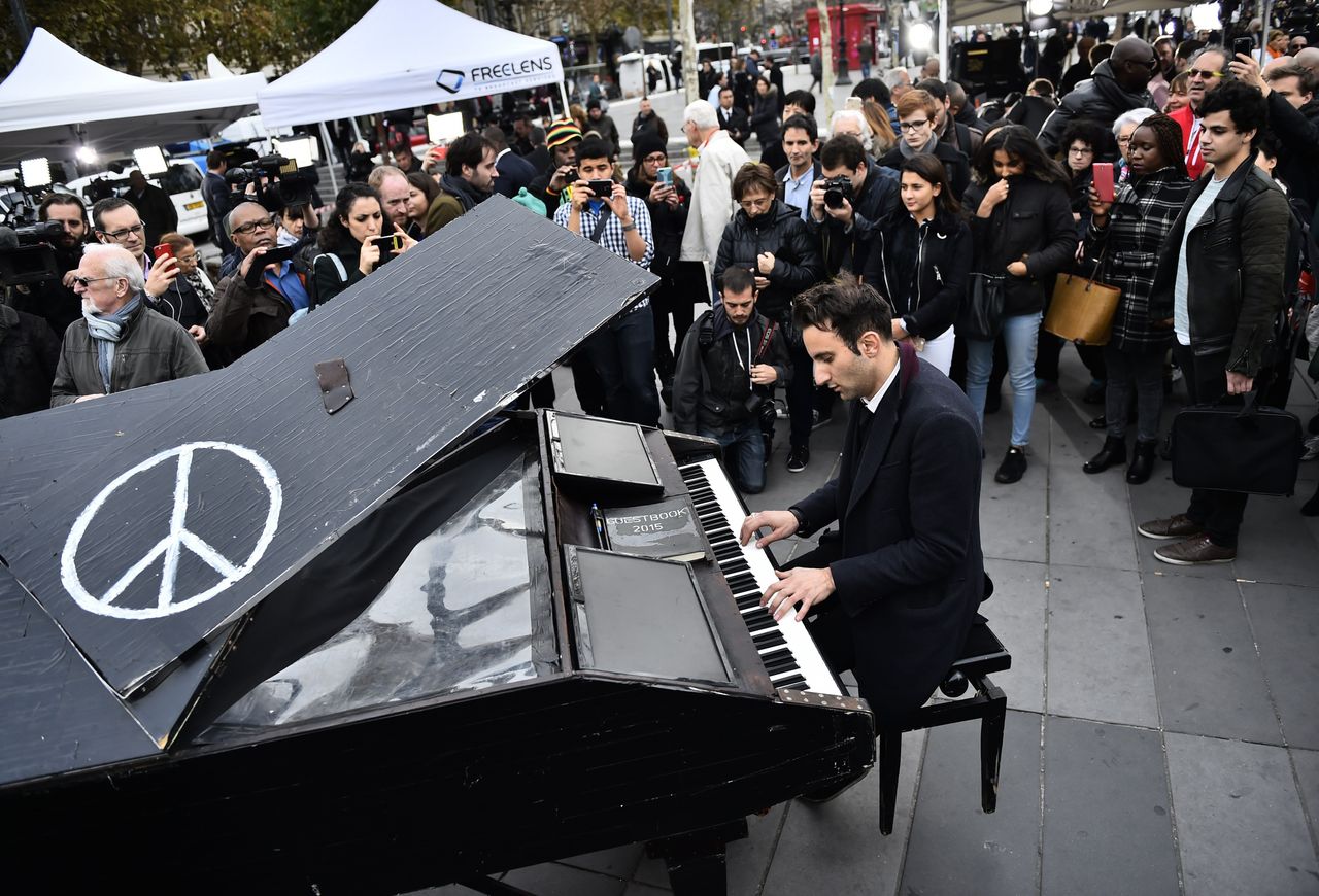 German Pianist Davide Martello, also known as Klavierkunst, plays piano as people gather after observing a minute of silence to pay tribute to victims of the attacks claimed by Islamic State, on November 16, 2015.