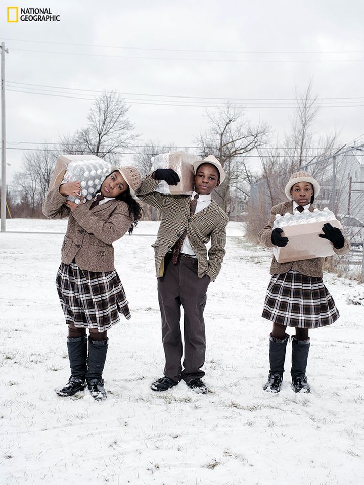 Siblings Julie, Antonio, and India Abram collect their daily allowance of bottled water from Fire Station #3. Located on Martin Luther King Avenue, it is one of five firehouses that have become water resource sites in Flint, Michigan.