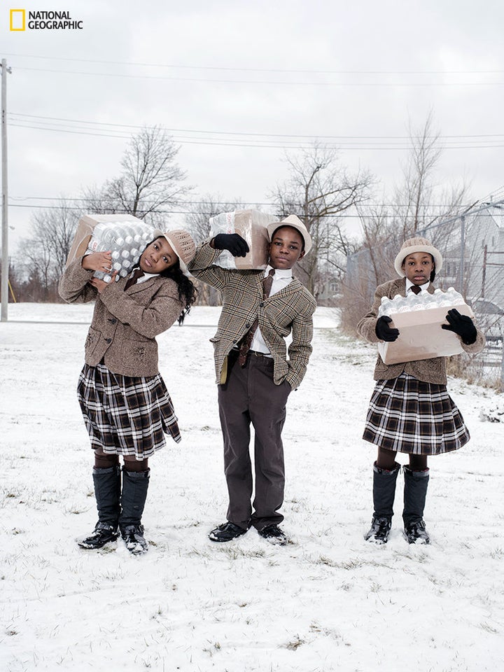 Siblings Julie, Antonio, and India Abram collect their daily allowance of bottled water from Fire Station #3. Located on Martin Luther King Avenue, it is one of five firehouses that have become water resource sites in Flint, Michigan.