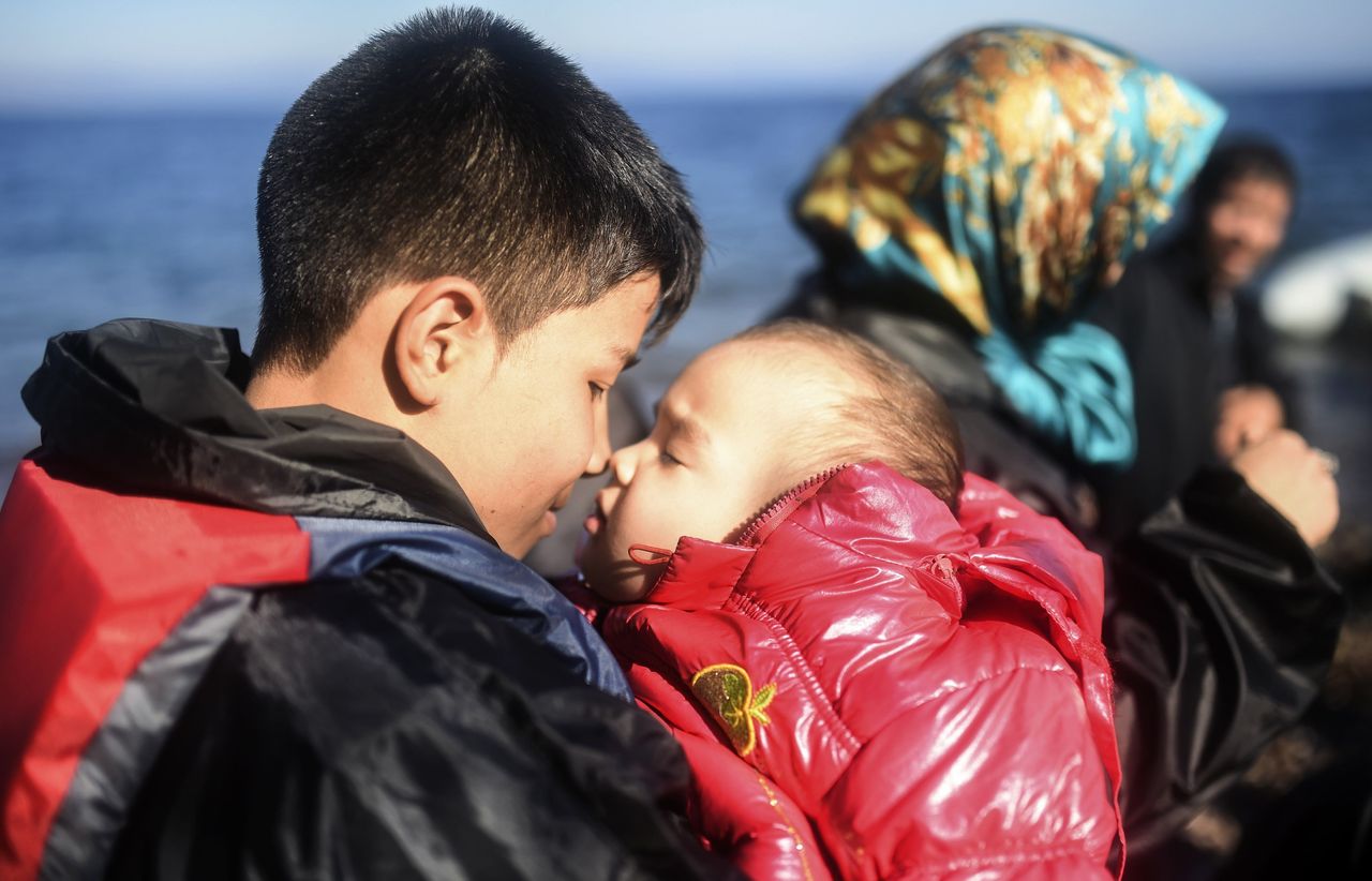 A youth embraces his sibling as refugees and migrants reach the shores of the Greek island of Lesbos after crossing the Aegean Sea from Turkey on November 12, 2015. 