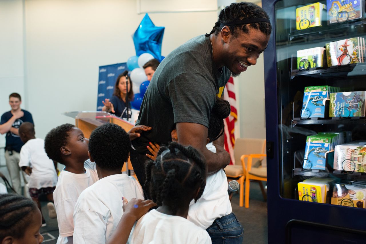 Redskins Robert Griffin III, center, gets hugs from the children at The Salvation Army in Anacostia. On Wednesday, July 8, 2015, JetBlues Soar with Reading program unveiled its first-of-its-kind book vending machines throughout SE in DC.