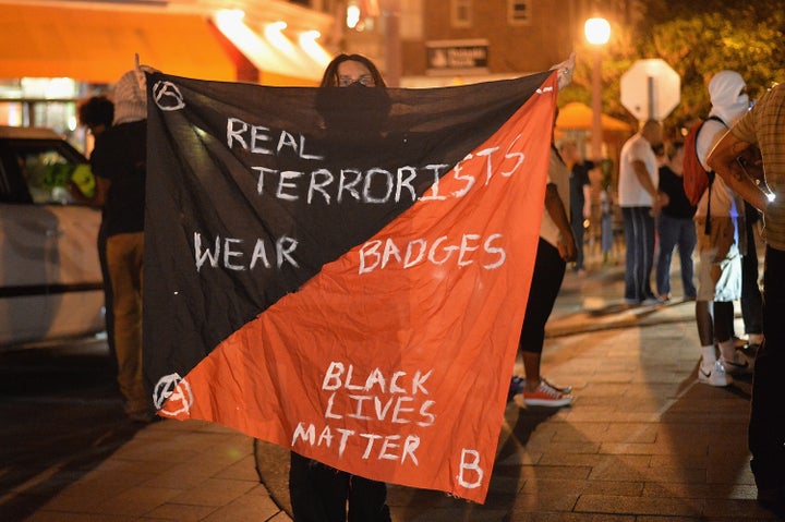 A woman holds a banner during a protest action through the central west end of St. Louis on Aug. 20, 2015.