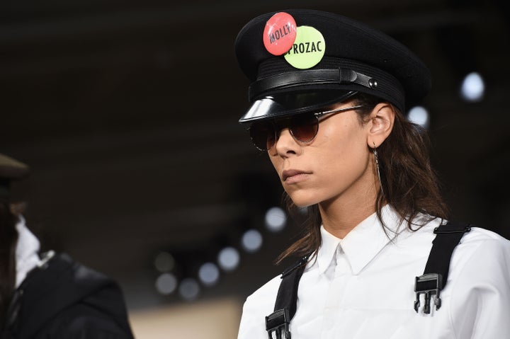 A Pyer Moss model wears buttons with the names of drugs and substances often used to medicate mental illness.