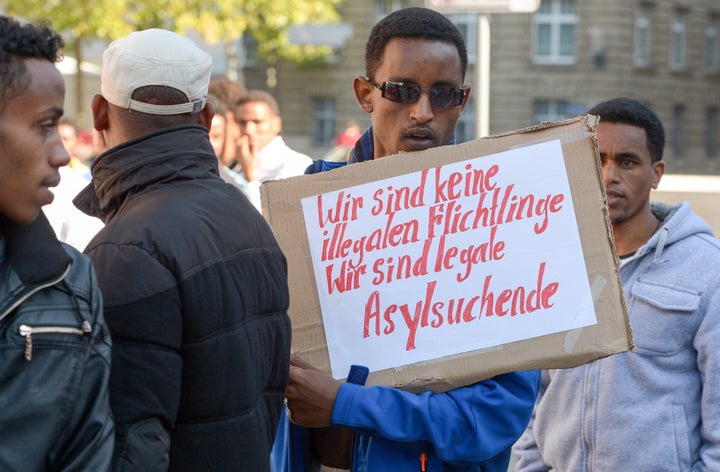 Eritreans are fleeing an authoritarian government and indefinite forced conscription. Here, a refugee from Eritrea holds a poster reading, "We are not illegal refugees - We are legal asylum-seekers," during a demonstration in Germany in October.