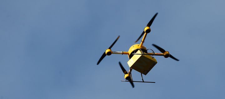 A quadcopter drone carrying a small parcel for delivery.