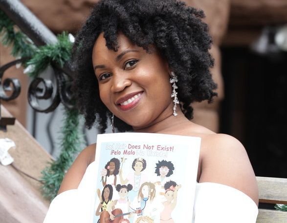 Sulma Arzu-Brown holding her book, <em>Bad Hair Does Not Exist!</em>