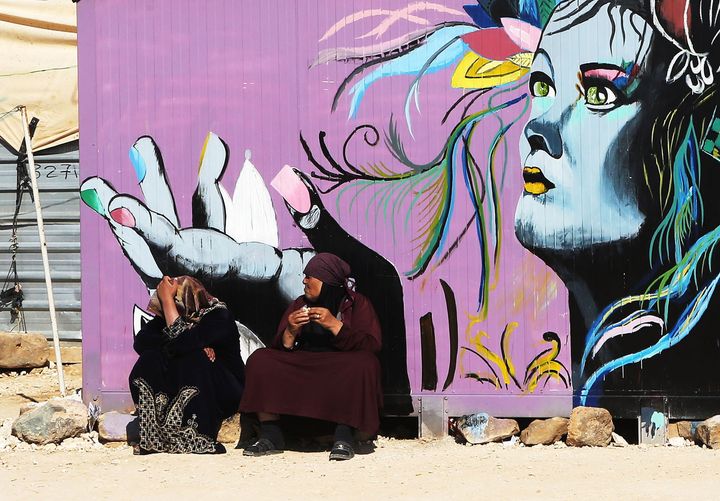 Syrian refugees women sit next to their colorful caravan on Feb. 2 in the creative Zaatari camp.