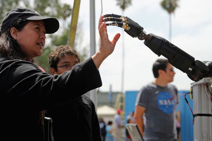 A woman reaches to touch a robotic arm developed by the Johns Hopkins University Applied Physics Laboratory, 2015.