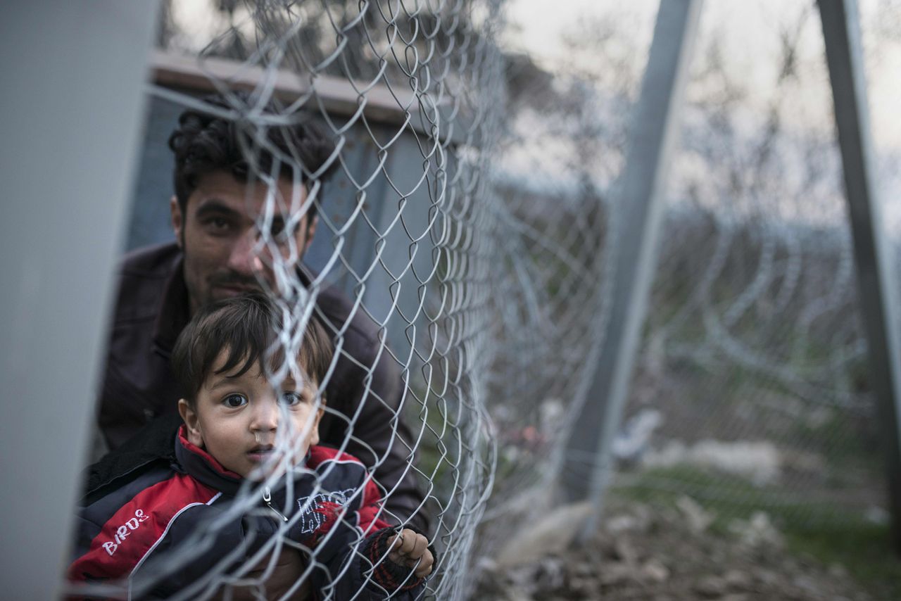 A man and a boy on the Greek side of the border look through a fence into Macedonia, which closed its borders to Afghans on Sunday.