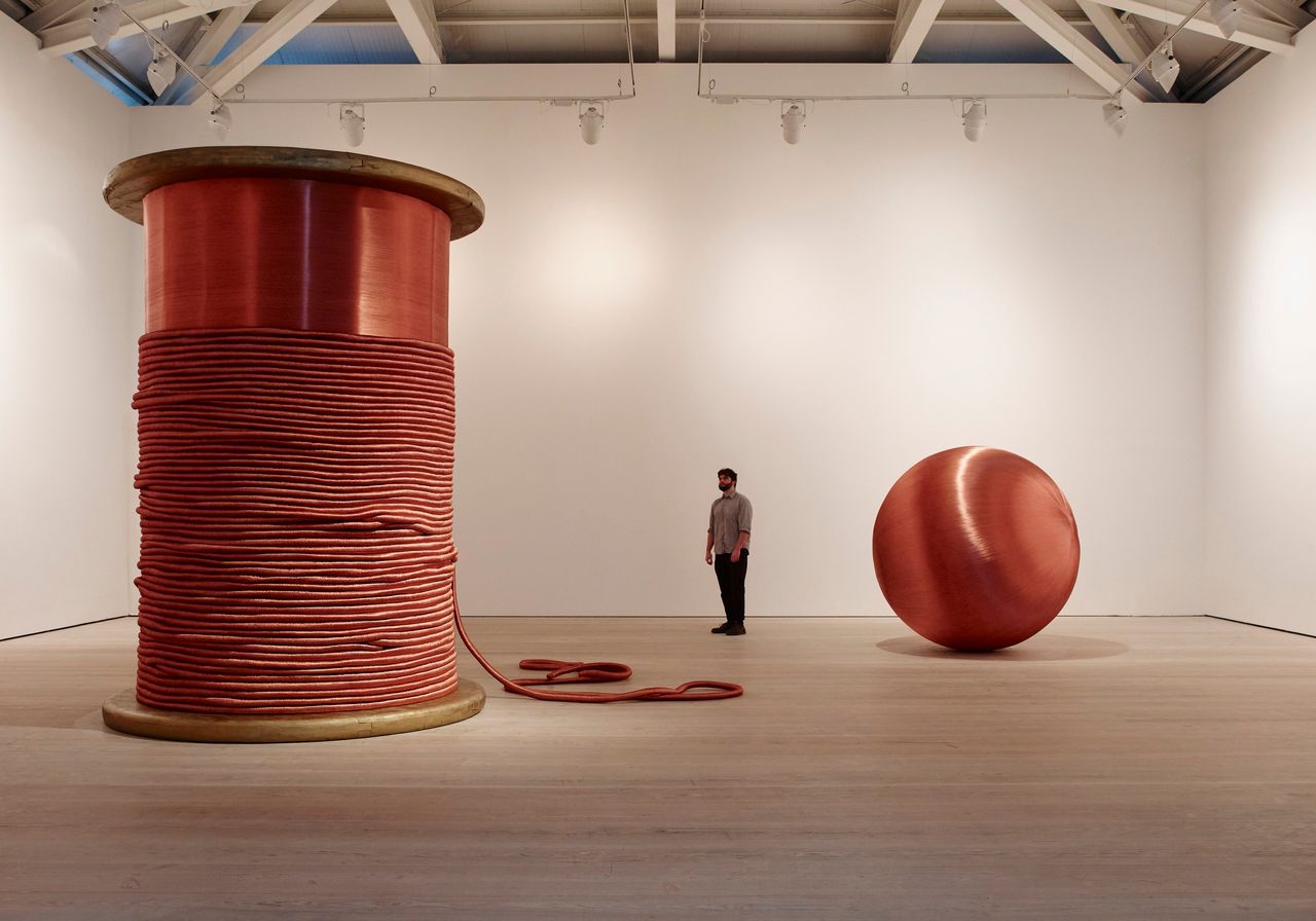 Alice Anderson: (Left) "Bound," 2011, bobbin made of wood and copper thread, 345 x 248 x 248 cm; (Right) "181 Kilometers," 2015, sculpture made after performances, copper thread, 200 cm (diameter), Image (c) Steve White, 2015, Courtesy of the Saatchi Gallery, London.