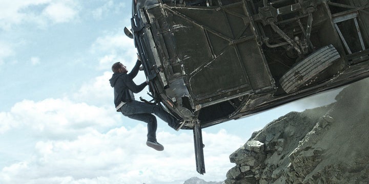 Actor Paul Walker hangs from a car while performing a stunt.