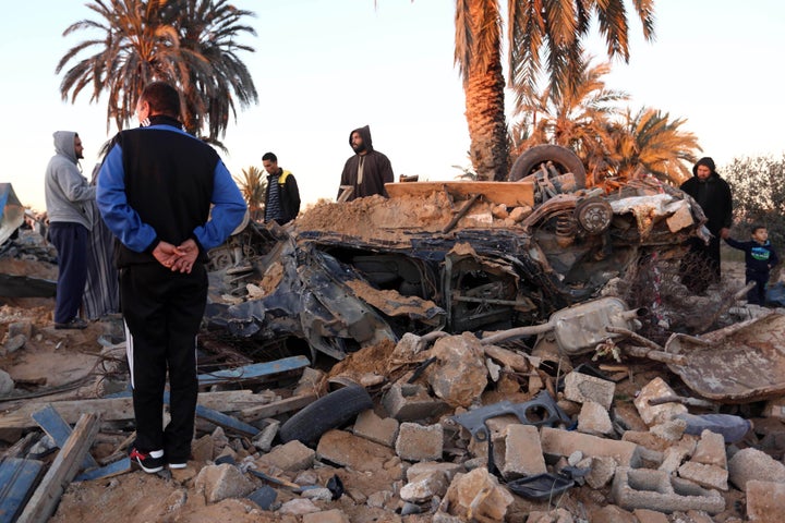 People gather around a damaged area after the U.S. carried out airstrikes against an Islamic State training camp in west