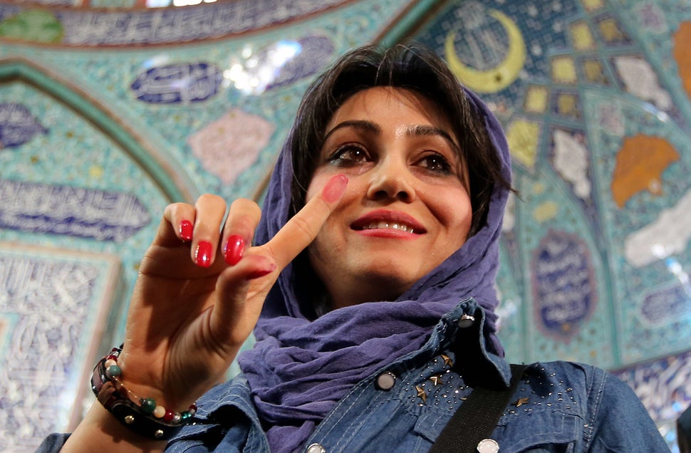 An Iranian woman proudly displays her ink-stained finger after casting her ballot at a polling station in Tehran on Feb. 