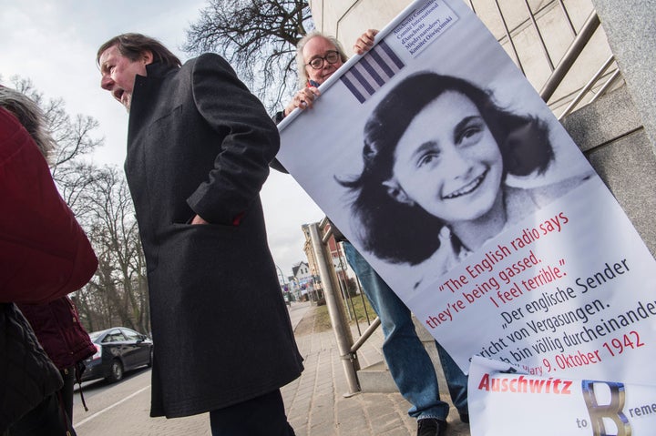 An activist rolls up a poster featuring Holocaust victim Anne Frank outside the Neubrandenburg court during the first day of the trial against Hubert Zafke.