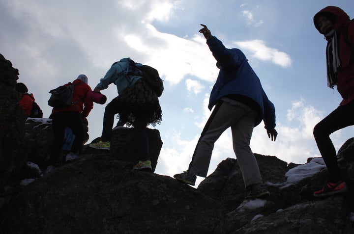 The Ascend hiking team balances on boulders as they make their way up a mountain.